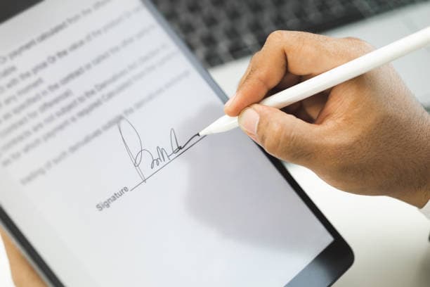 Main signant un contrat sur tablette avec un stylet pour une signature electronique
